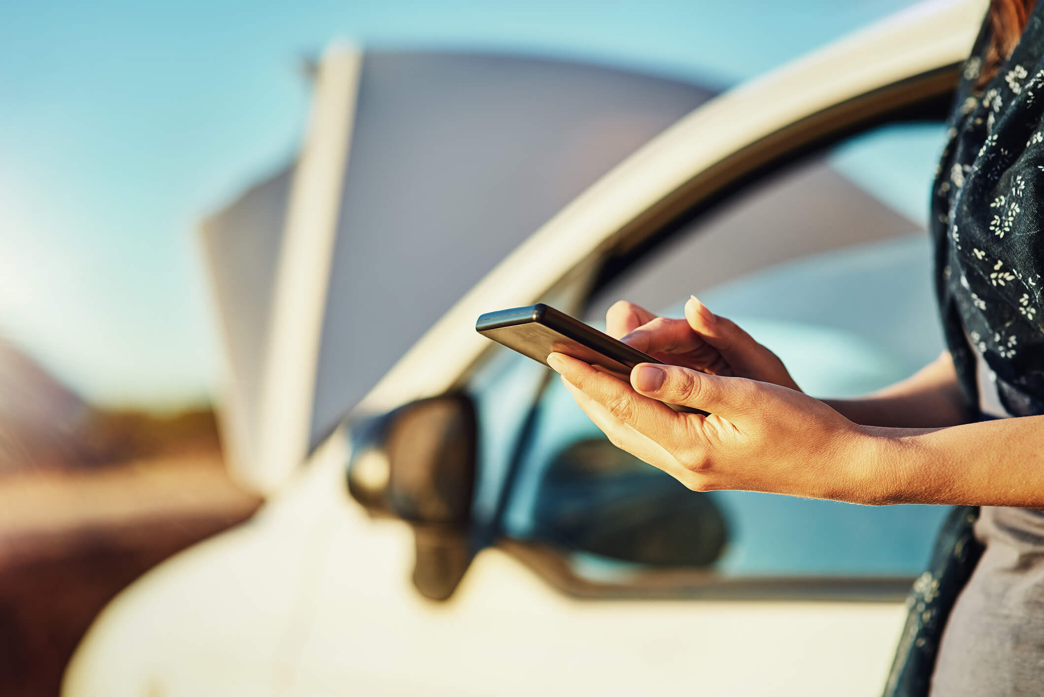 Une femme au téléphone à côté d'une voiture endommagée